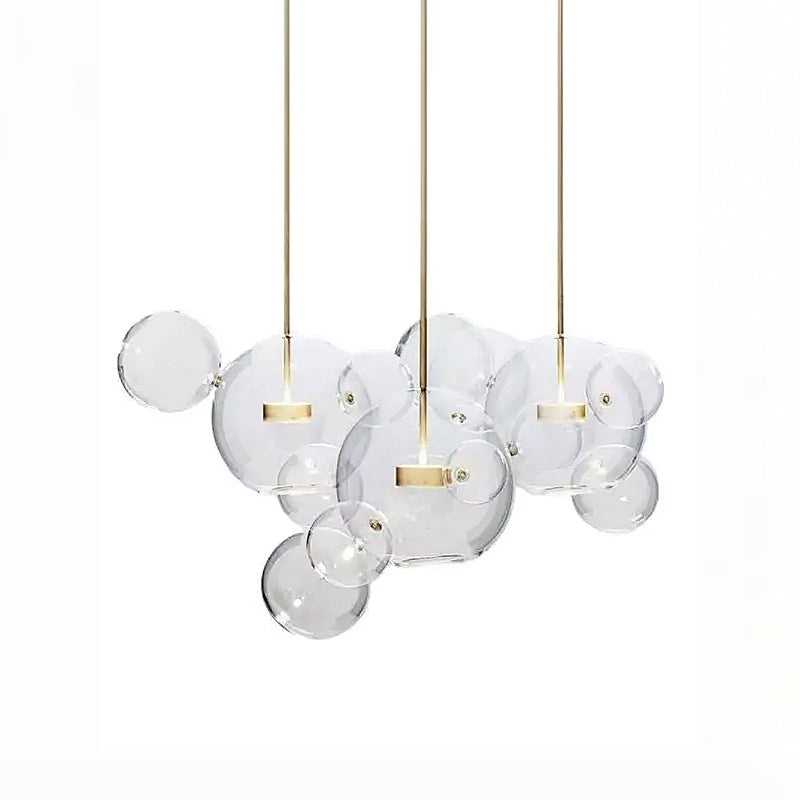 Three Clérachic glass sphere pendants with gold stems, clear spheres overlapping between them, on a white backdrop.