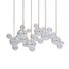 Wide Clérachic glass sphere installation with many pendants hung at different heights, on a white backdrop.