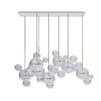 Wide Clérachic glass sphere installation seen from the front, with dark cables and clear spheres, on a white backdrop.