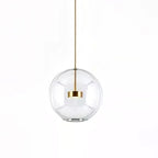 Clérachic clear glass globe pendant with a gold disc at its centre, on a white backdrop.