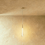 Clérachic slim frosted teardrop pendant with a brass cone cap and round canopy, glowing warm against plaster.