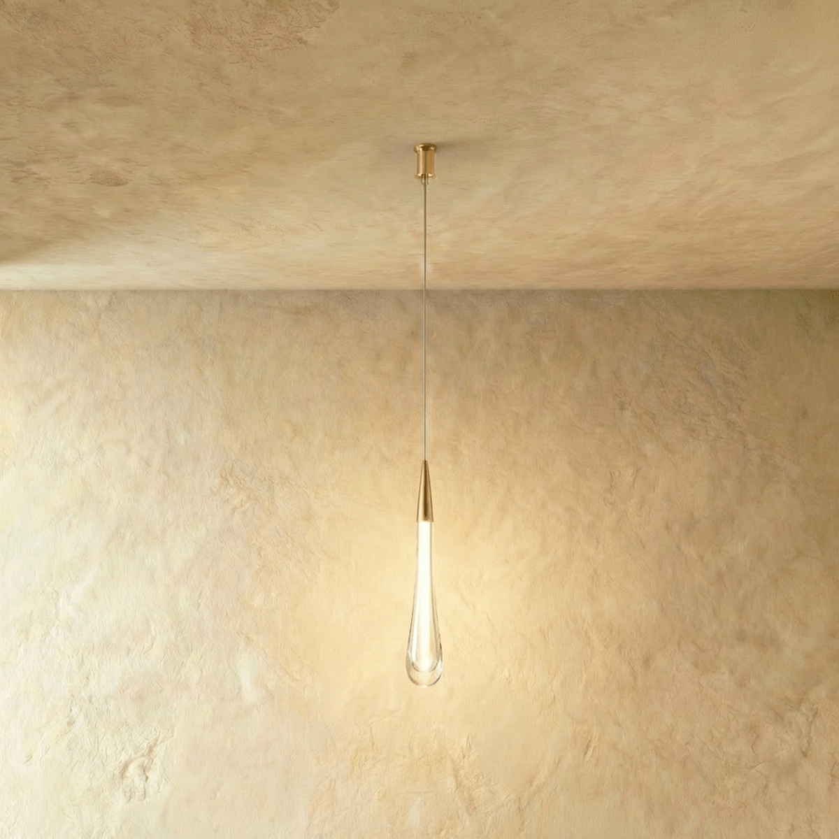 Clérachic long frosted glass teardrop pendant with a brass cone cap and slim canopy, lit on a limewash backdrop.