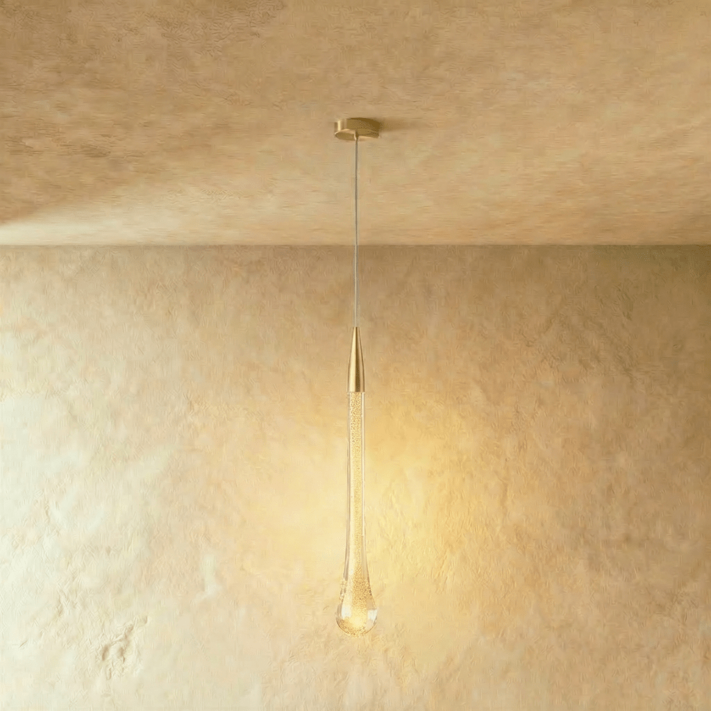 Clérachic tall teardrop pendant with a brass cap and a bubbled glass drop, glowing amber, with a round brass canopy.
