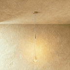 Clérachic tall teardrop pendant with a brass cap and a bubbled glass drop, glowing amber, with a round brass canopy.