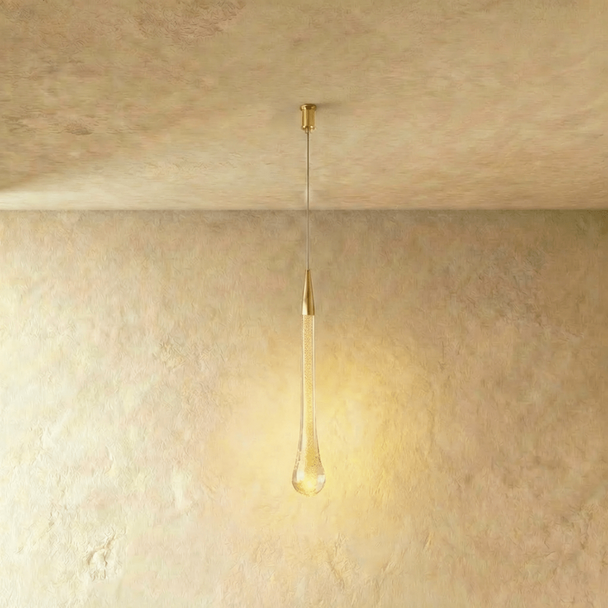 Clérachic extra-long teardrop pendant in bubbled glass with a brass cone, lit warmly under a slim cylindrical canopy.