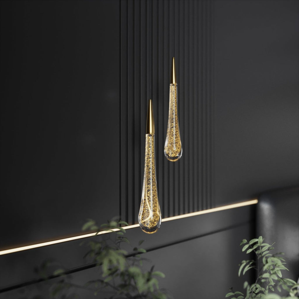 Clérachic pair of brass-capped teardrop pendants with gold-flecked bubbled glass, hung against dark fluted panelling.