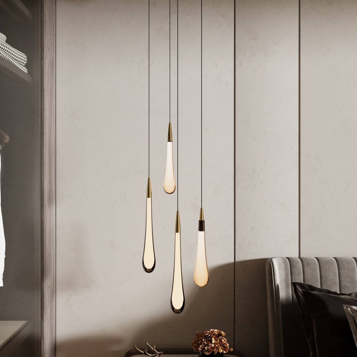 Clérachic four milky white teardrop pendants with brass caps at varied heights beside a wardrobe and grey sofa.