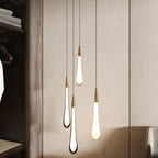 Clérachic four opal white teardrop pendants with brass caps hanging together beside a wardrobe in a neutral room.