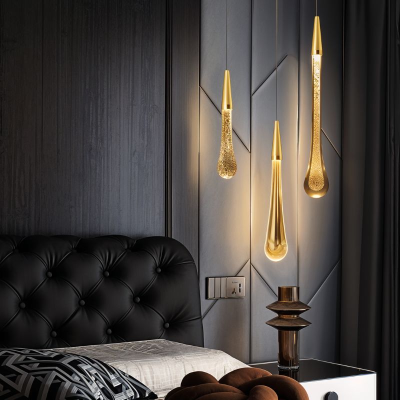 Clérachic three brass teardrop pendants in clear, amber and bubbled glass above a tufted black headboard.