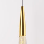 Clérachic close-up of the polished brass cone cap where the glass drop meets the cable, with bubbles lit inside the glass.