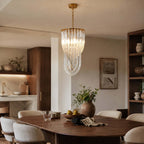 A taller, narrower version of this Clérachic pendant, with curved glass rods looping below a gold crown, hangs in an open kitchen and dining room.