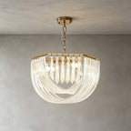 A wide, shallow Clérachic pendant with layered glass rods and gold fittings hangs on a chain in front of a grey plaster wall.