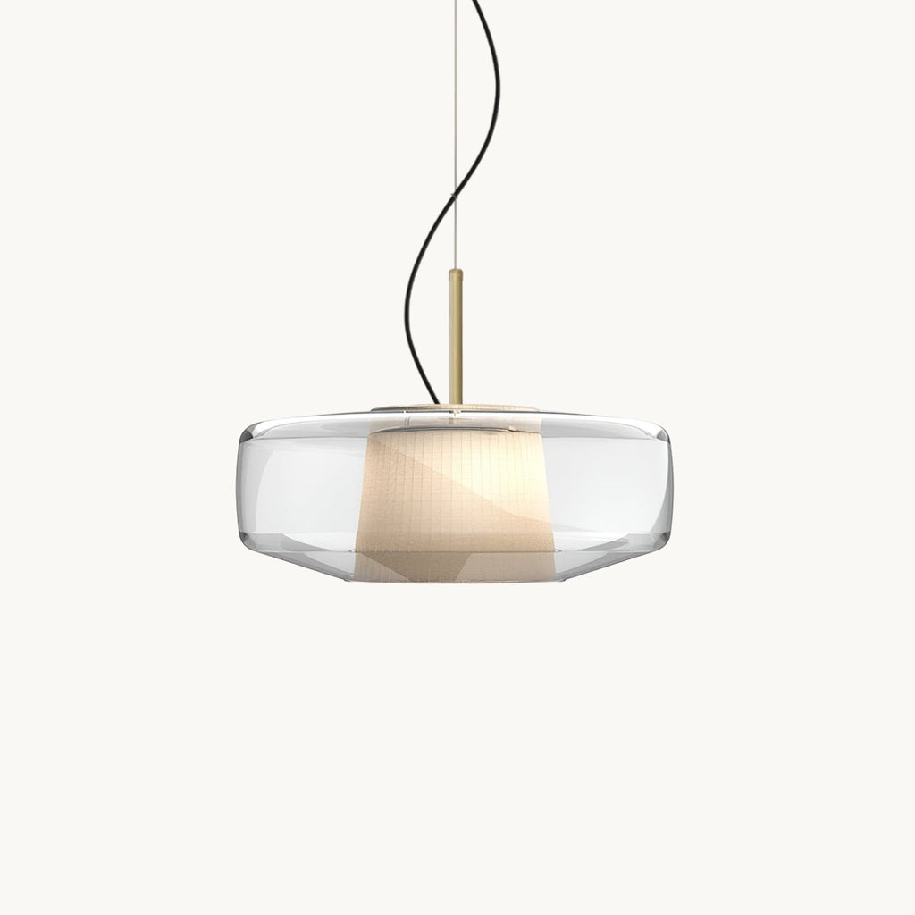 A Clérachic pendant with a wide clear glass shade, a pleated white inner shade and a brass stem, on a plain white backdrop.