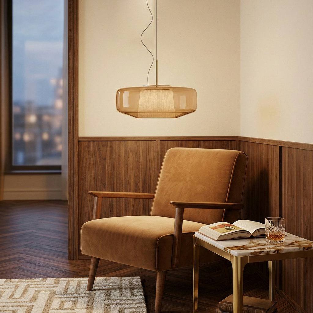 An amber glass version of this Clérachic pendant lit beside a tan velvet armchair, in a room with walnut wall panelling.