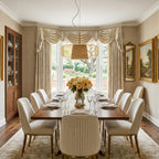 This Clérachic pendant hangs above a long walnut dining table in a formal room, with cream upholstered chairs and draped curtains behind.