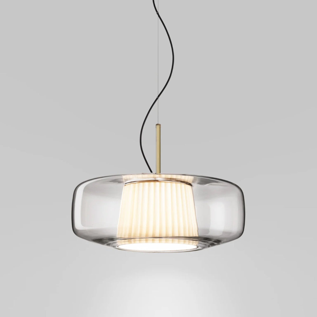 Front view of the clear glass Clérachic pendant on a pale grey backdrop, showing the pleated inner shade and the brass stem.