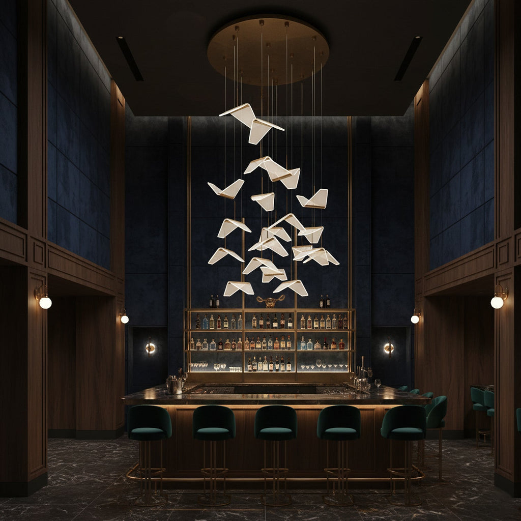 Folded shades from this Clérachic pendant light float above a dark bar with green stools, under a round gold ceiling plate.