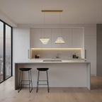 Two folded shades from this Clérachic pendant light hang side by side from a gold bar above a white kitchen island.