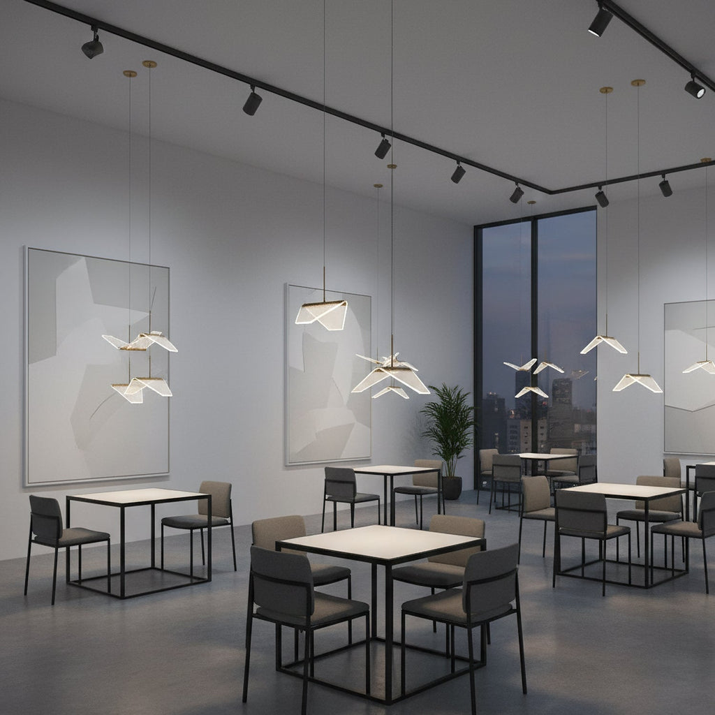 In a grey café space with track lighting and square tables, this Clérachic pendant light hangs folded shades at varied heights.