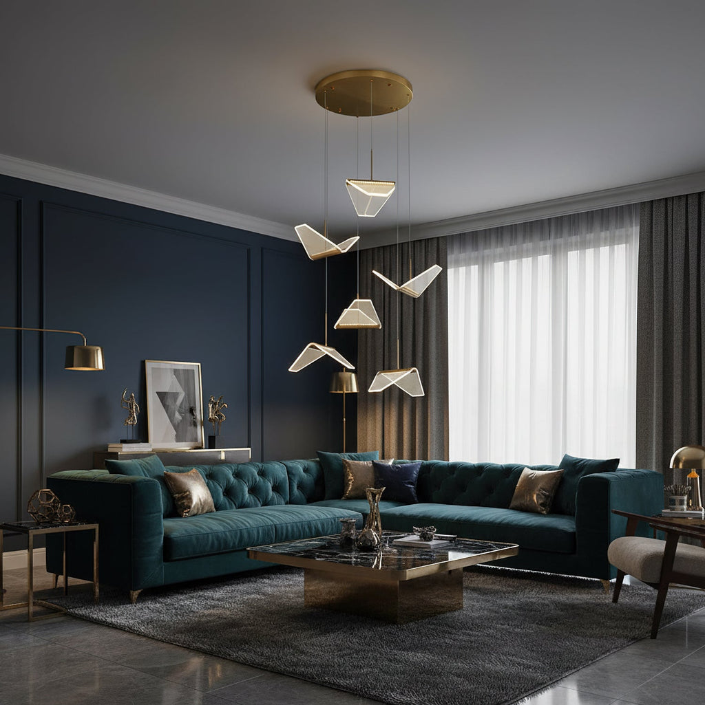 This Clérachic pendant light hangs folded shades above a teal Chesterfield sofa, with a dark blue wall behind.