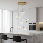 Folded shades from this Clérachic pendant light hang above a white marble island with black stools in a bright kitchen.