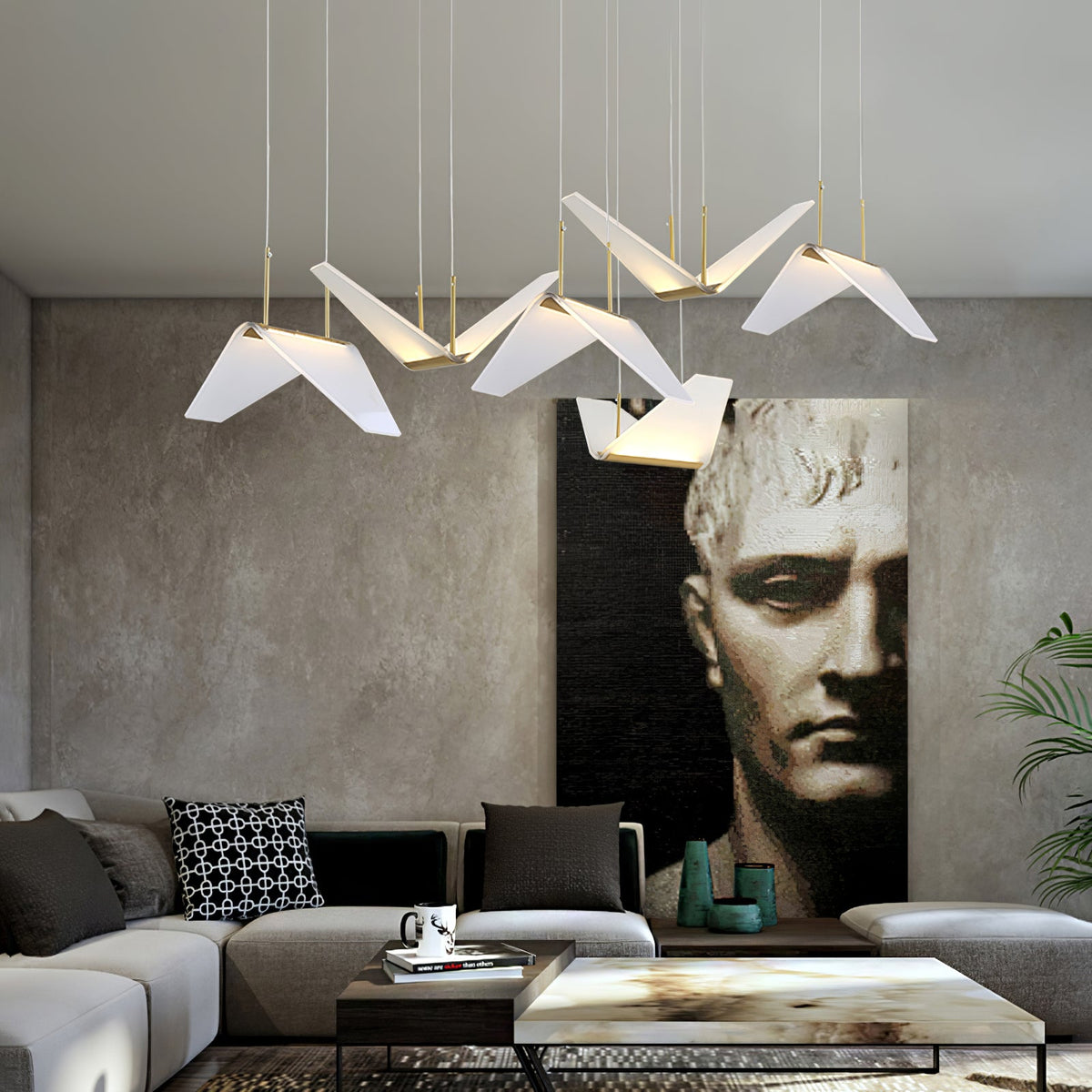 Folded white shades of this Clérachic pendant light hang over a grey sofa, with a large dark portrait on a textured wall.