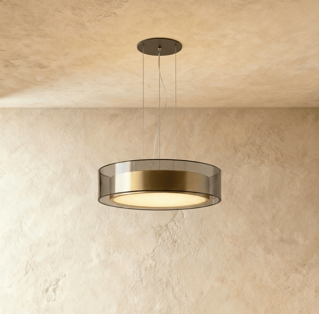 Clérachic's pendant light, a smoked glass drum with a brushed brass band glowing warm on thin cables.