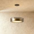 Clérachic's pendant light, a smoked glass drum with a brushed brass band glowing warm on thin cables.