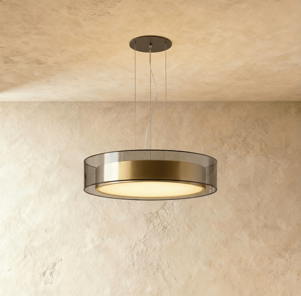 A side view of the Clérachic pendant light, its smoked glass and brass drum glowing softly overhead.