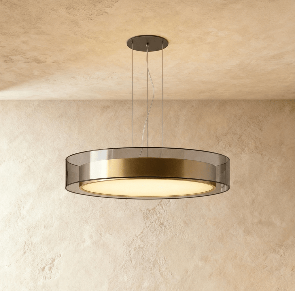 Clérachic's pendant light, its frosted diffuser glowing warm beneath a brushed brass and glass drum.