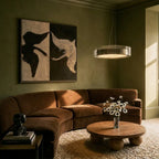 Clérachic's pendant light glowing warm in a moss-green living room beside a curved velvet sofa.