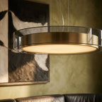 A close detail of the Clérachic pendant light's glass and brass drum against a green painted wall.