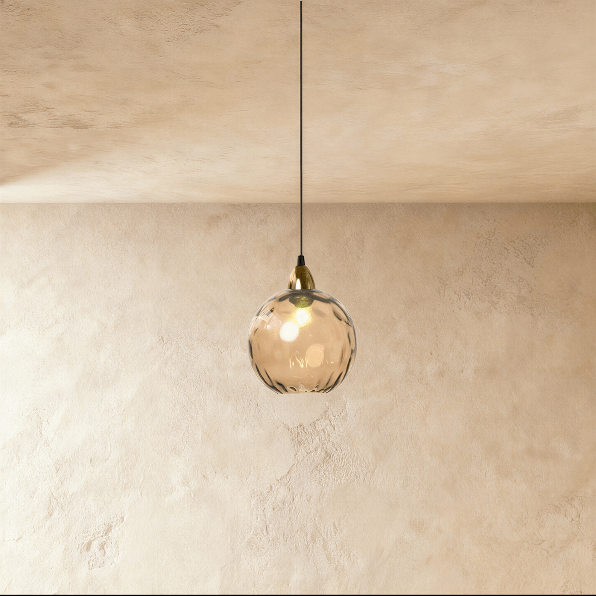 Clérachic gold pendant light with a cognac-toned blown glass globe, its dimpled texture catching warm light.