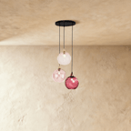 Clérachic gold pendant cluster with three blown glass globes in pink tones, suspended at staggered heights from a round canopy.
