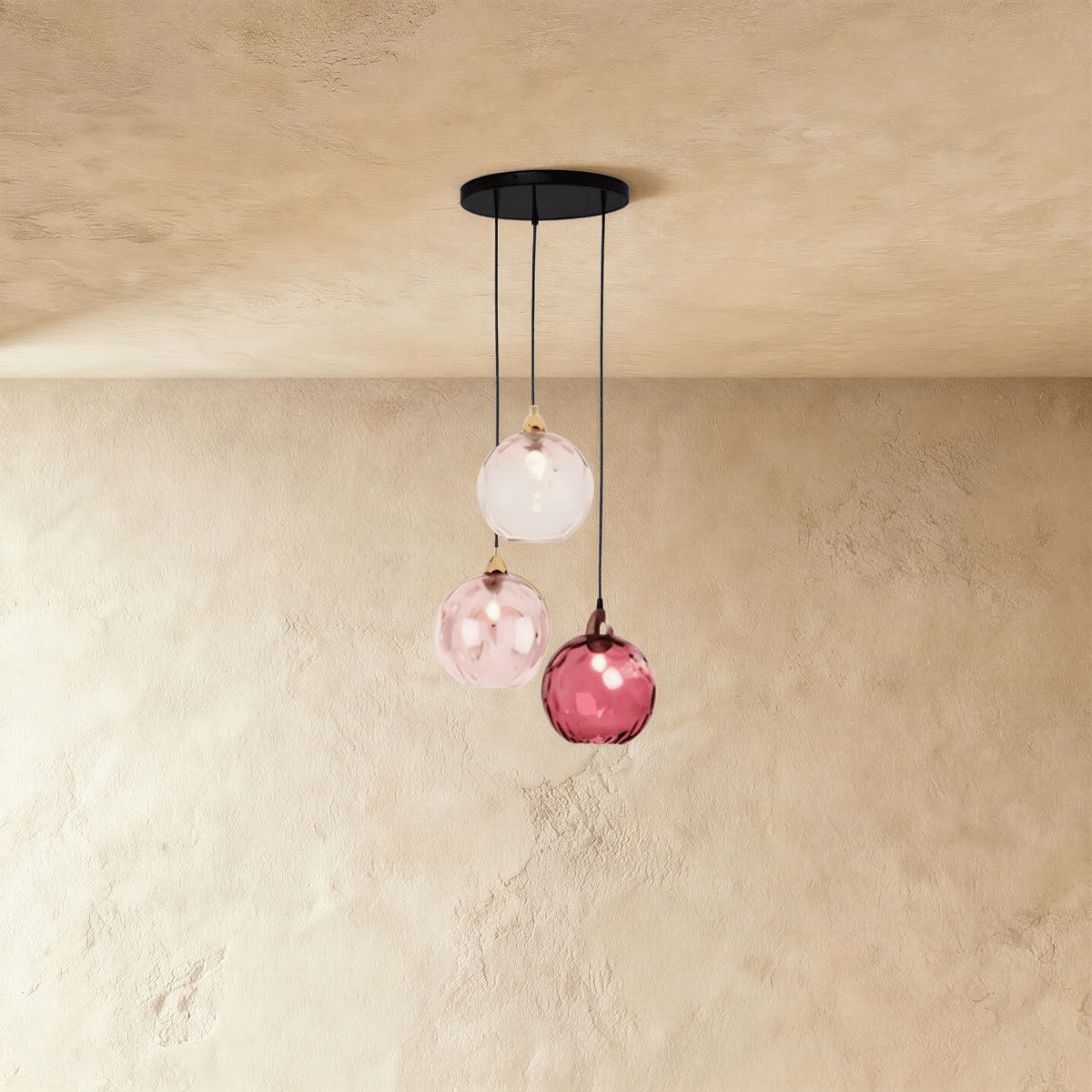 Clérachic gold pendant cluster with three blown glass globes in pink tones, suspended at staggered heights from a round canopy.