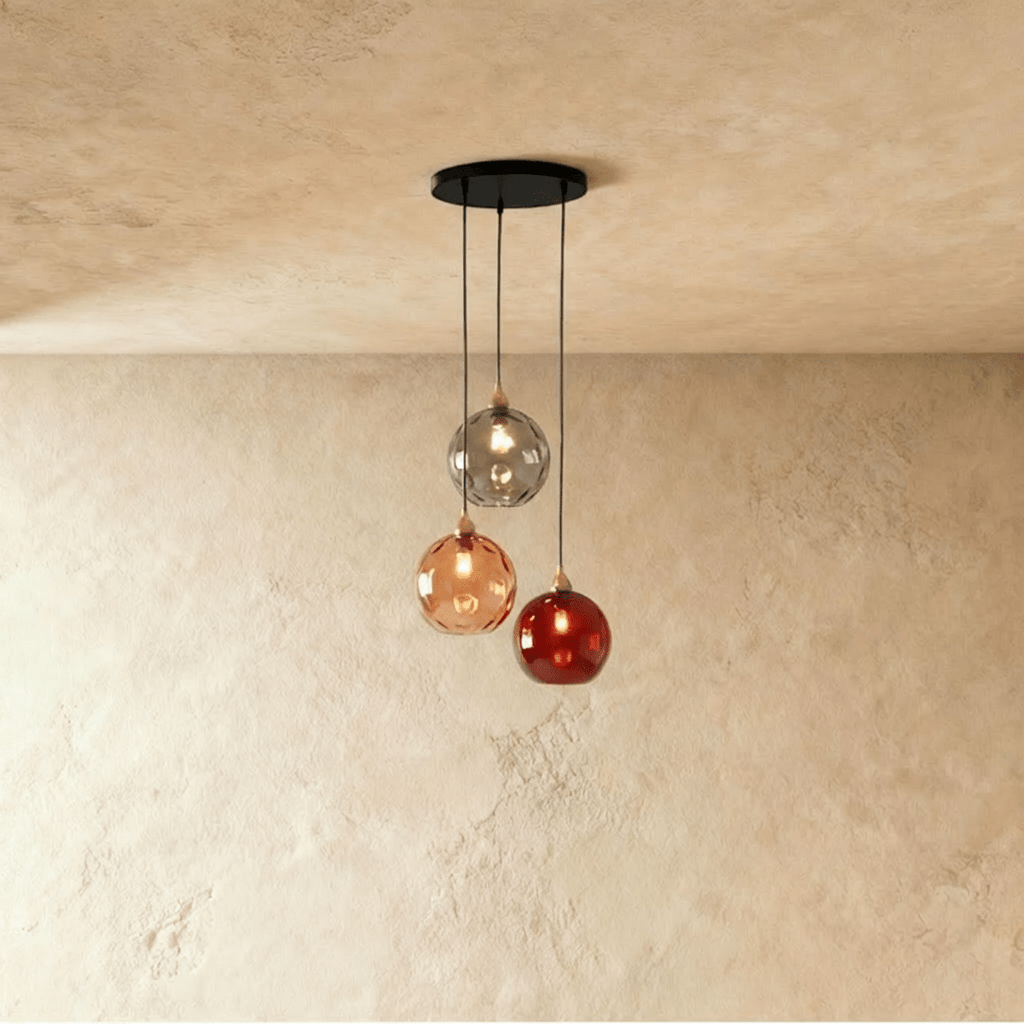 Clérachic gold pendant cluster with three blown glass globes in gray, amber and red tones on a black round canopy.