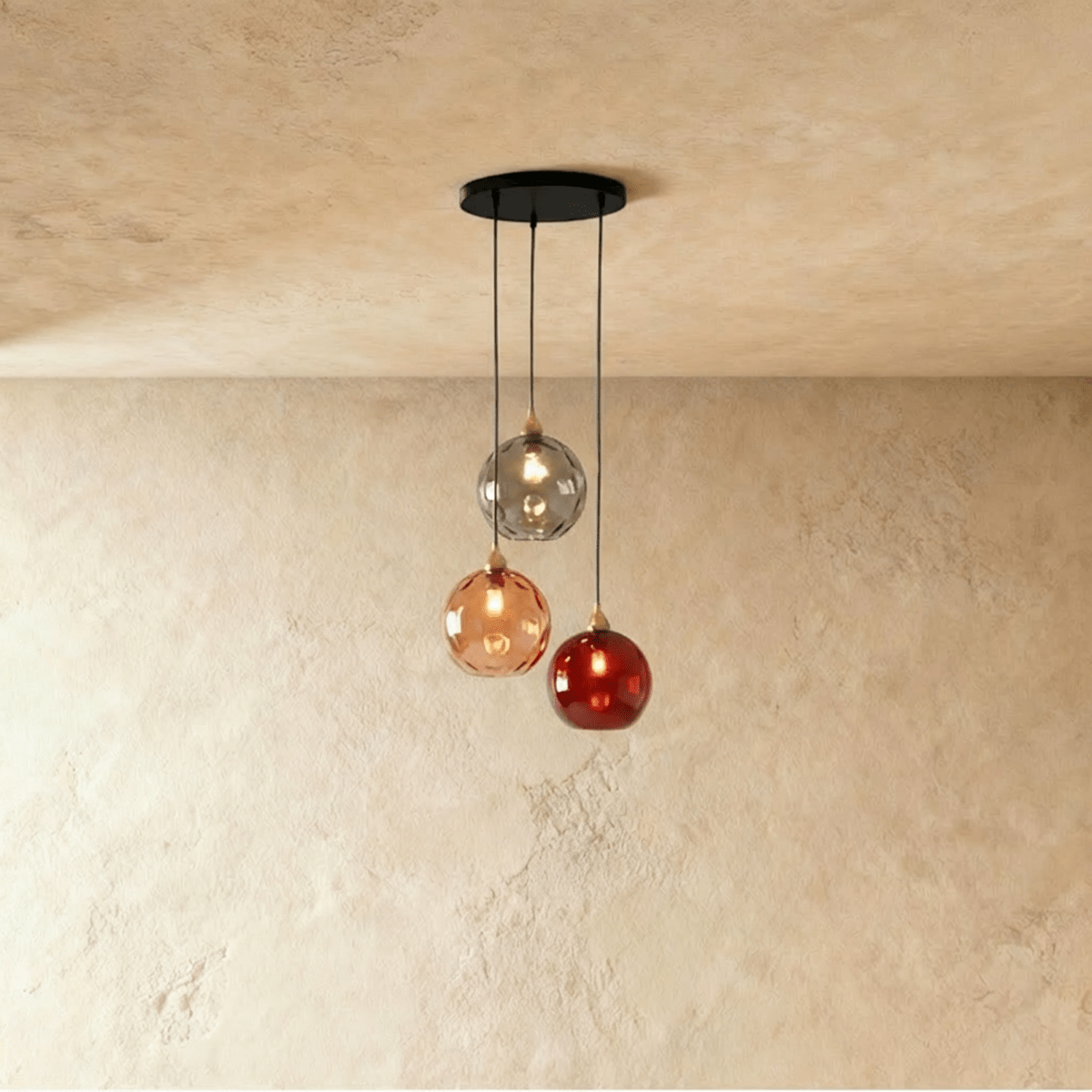 Clérachic gold pendant cluster with three blown glass globes in gray, amber and red tones on a black round canopy.