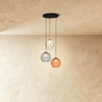 Clérachic gold pendant cluster with three blown glass globes in white, gray and orange tones on a round canopy.
