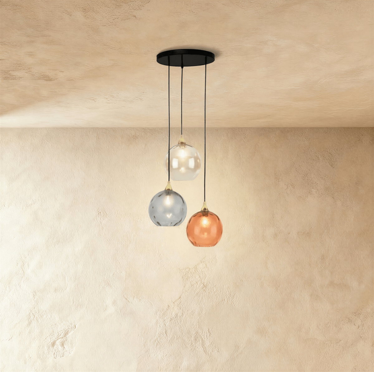Clérachic gold pendant cluster with three blown glass globes in white, gray and orange tones on a round canopy.