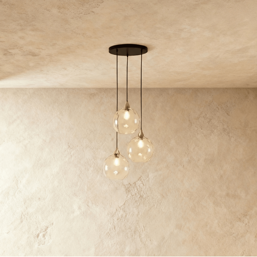Clérachic gold pendant cluster with three clear and amber blown glass globes suspended from a round brass canopy.