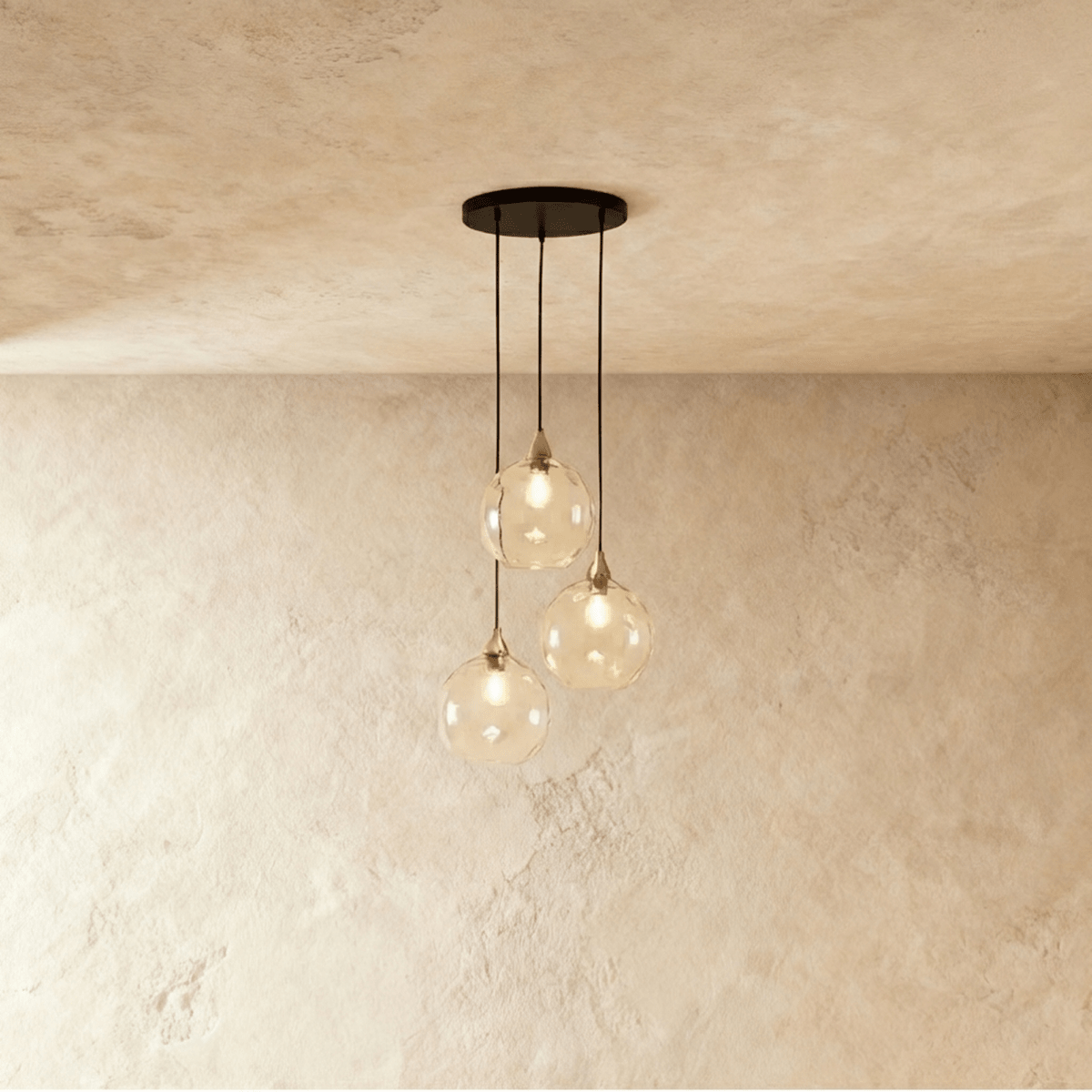 Clérachic gold pendant cluster with three clear and amber blown glass globes suspended from a round brass canopy.