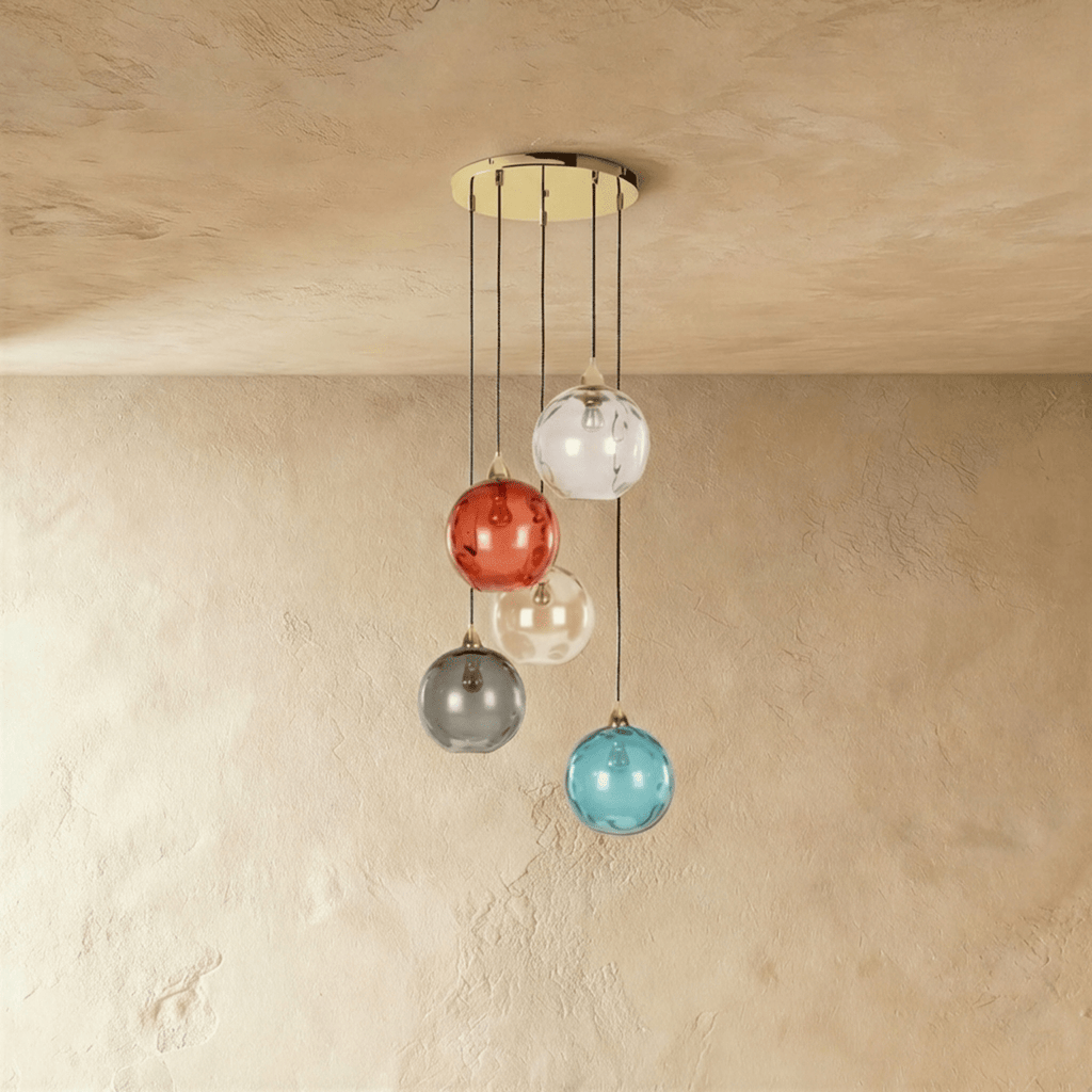Clérachic gold pendant cluster with five blown glass globes in mixed tones cascading from a round black canopy.