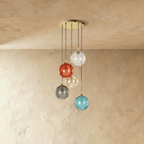 Clérachic gold pendant cluster with five blown glass globes in mixed tones cascading from a round black canopy.
