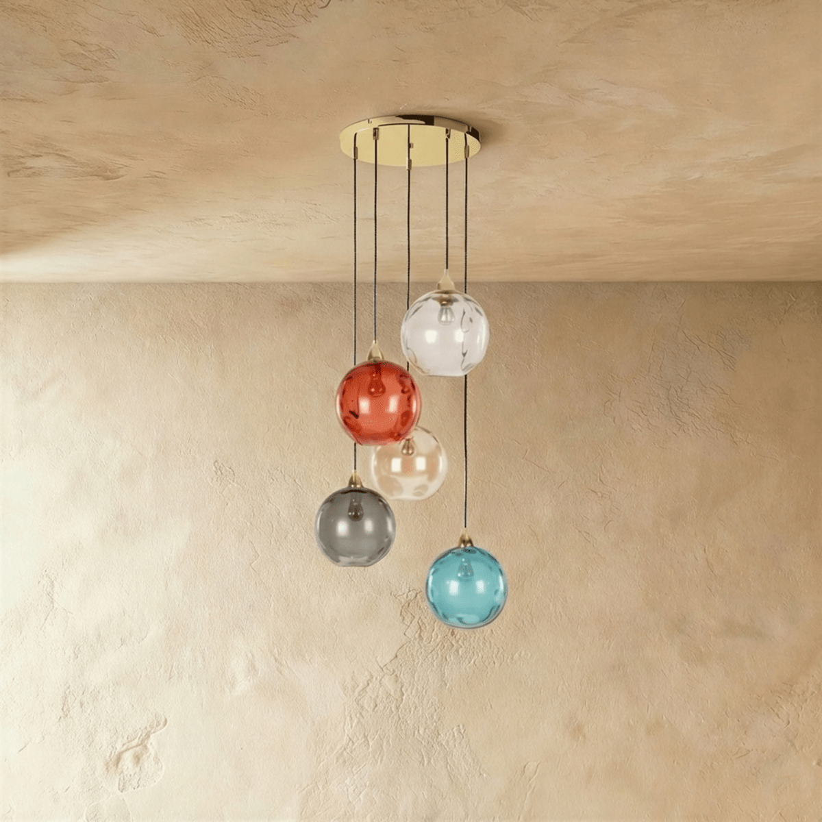 Clérachic gold pendant cluster with five blown glass globes in mixed tones cascading from a round black canopy.