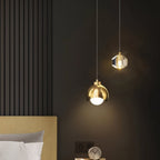 Clérachic pendant light in gold lit warm beside a bed, dome and faceted-glass shades glowing softly.