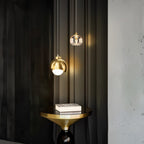 Clérachic pendant light in gold lit warm above a round brass side table stacked with books.