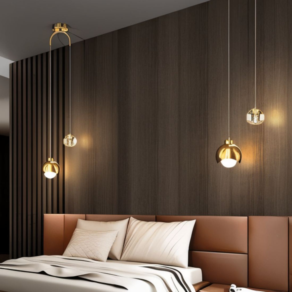 Clérachic pendant lights in gold lit warm above a leather headboard, hung from two ceiling canopies.