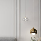 Clérachic pendant light detail in gold, the dome and faceted-glass shades against a panelled wall.