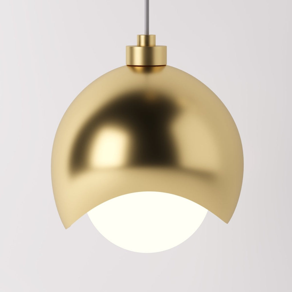 Clérachic pendant light dome shade in gold, its polished curve catching light above the opal diffuser.
