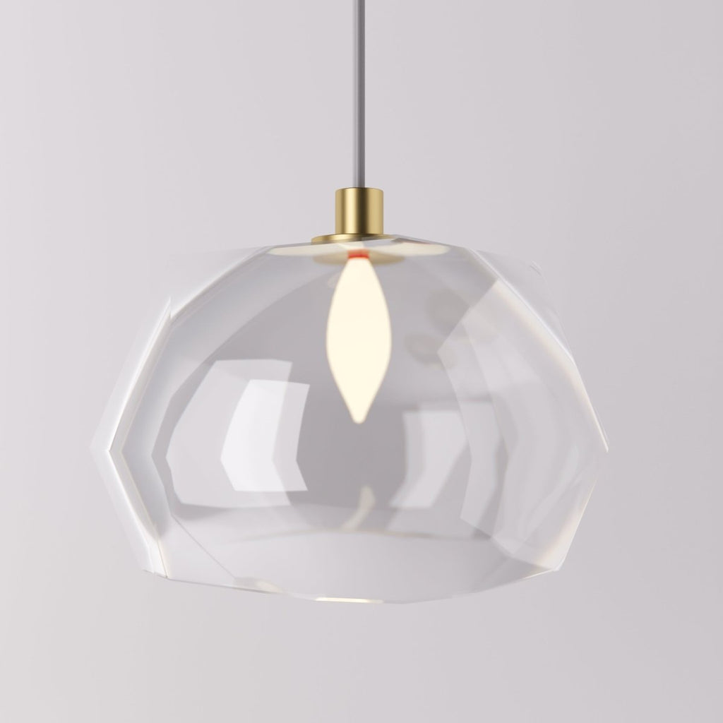 Clérachic pendant light faceted glass shade lit warm, its angled clear panels on a brass cord fitting.
